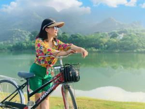 a woman riding a bike in front of a lake at AQUARIUS GARDEN NINH BÌNH in Giá Sơn
