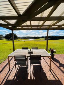una mesa de madera y sillas en un patio en Perfect weekend getaway plus golf at your doorstep, en Salamander Bay