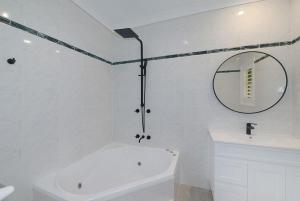 a white bathroom with a tub and a mirror at The Acreage Boutique Guesthouse in North Avoca