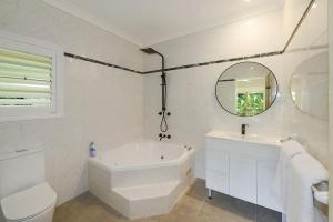 a white bathroom with a tub and a sink and a mirror at The Acreage Boutique Guesthouse in North Avoca