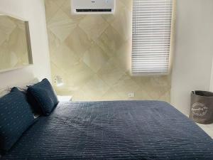 a bedroom with a bed with a blue comforter and a window at Costa Relax 2 in Guayama