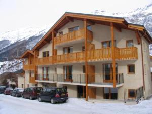un grand immeuble avec des voitures garées dans la neige dans l'établissement Appartement 7 pers. au centre de Val Cenis, proche pistes et commodités - FR-1-508-7, à Lanslevillard 5 autres photos