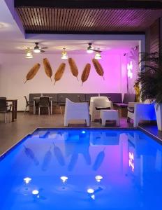 una piscina con iluminación púrpura, mesas y sillas en Remfort Hotel, en Santa Ana