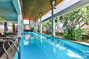 uma grande piscina com cadeiras e mesas e um edifício em Indra Hotel em Phnom Penh