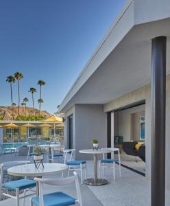 eine Terrasse mit Tischen, Stühlen und Palmen in der Unterkunft Twin Palms Resort - A Gay Men's Resort in Palm Springs