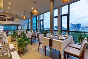 a restaurant with tables and chairs and large windows at Indra Hotel in Phnom Penh
