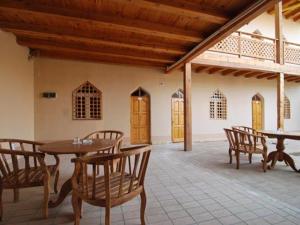 Habitación con mesas de madera y sillas en un edificio en Islambek Khiva, en Khiva