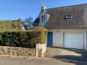 una casa blanca con un garaje y un seto en Maison Bénodet, 4 pièces, 8 personnes - FR-1-481-126 en Bénodet