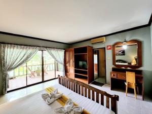1 dormitorio con cama, escritorio y espejo en Kata Garden Resort SHA Extra Plus, en Kata Beach