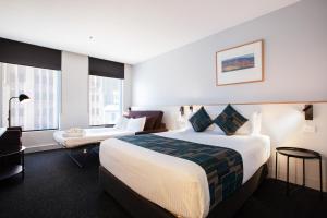a hotel room with a large bed and a desk at CitiClub Hotel Melbourne in Melbourne