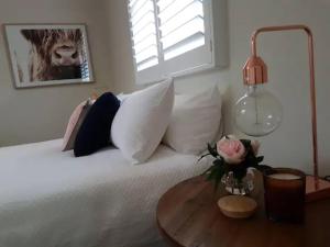 ein Bett mit Kissen und einen Tisch mit einer Blumenvase in der Unterkunft 105A Sale St STYLISH IN THE HEART OF ORANGE in Orange