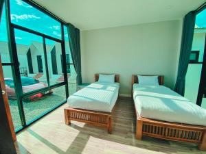 two beds in a room with a large window at เดอนาปัว วิลล่า in Ban Chalaeng