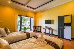 2 camas en una habitación con paredes amarillas en Grand Ball Beach Garden en Nusa Penida