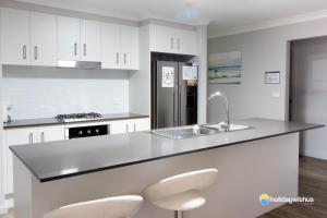 uma cozinha branca com um lavatório e uma bancada em Sunrise em Sussex inlet