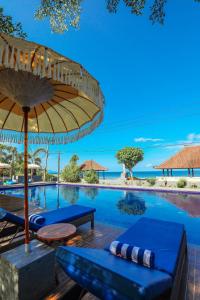een zwembad in het resort met stoelen en een parasol bij Grand Ball Beach Garden in Nusa Penida