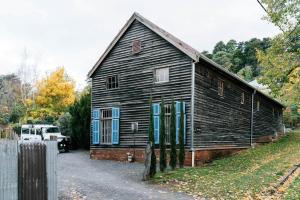 an old wooden house with blue windows and a fence at The Barn Daylesford in Daylesford