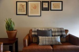 a brown leather couch with a pillow and pictures on the wall at Circa Ruby Mint Daylesford in Daylesford