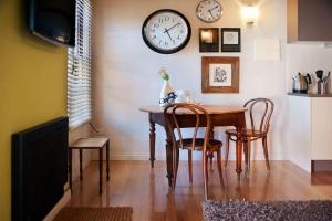 a dining room with a table and chairs and a clock on the wall at Circa Ruby Mint Daylesford in Daylesford