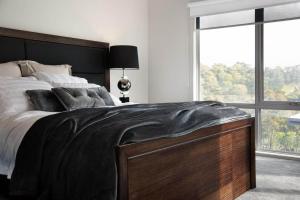 a bedroom with a large bed with a black blanket on it at Amelia Daylesford in Daylesford