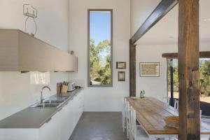 uma cozinha com armários brancos e uma mesa de madeira em Lithia Guest House - Daylesford Region em Hepburn Springs