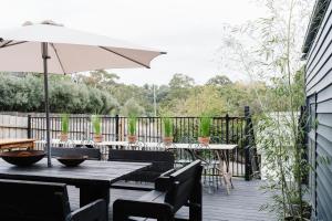 a patio with tables and chairs and an umbrella at The Oxford - Hepburn Springs Daylesford in Hepburn Springs