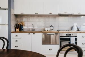 a kitchen with white cabinets and a sink and a table at Candlebark Daylesford in Daylesford