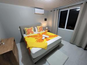 1 dormitorio con 1 cama con manta amarilla y ventana en Maddy's House en Maatea
