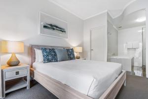 a white bedroom with a large bed and a bathroom at Mirra Chana in Mooloolaba