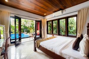 a bedroom with a large bed and large windows at Pukakoo Villas and Suite by Supala in Ubud