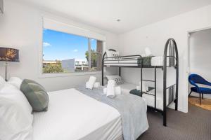 Un dormitorio con una litera y una silla. en The Cove - Luxury Waterfront Accommodation, en Safety Beach