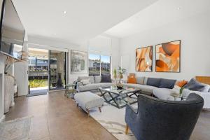 Una sala de estar con sofás y una mesa. en The Cove - Luxury Waterfront Accommodation, en Safety Beach