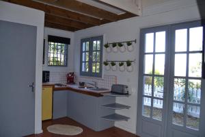 a kitchen with a counter and a sink and windows at La Petite Kaz Dans la Savane in Fleurimont
