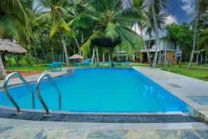 a pool at a resort with palm trees at Lake Edge Holiday Inn in Tissamaharama