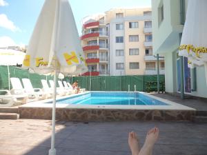 a person with their feet up next to a swimming pool at Family Hotel Romantik in Sunny Beach