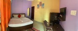 a small bedroom with a bed and a television at MANIK GUEST HOUSE in Rishīkesh