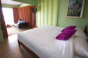 a bedroom with a white bed with a purple pillow at Mhork Buri Resort in Khao Kho