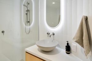 un bagno bianco con lavandino e specchio di The Cove Noosa - Apartment 13 a Noosa Heads