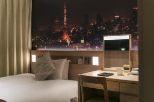 a hotel room with a bed and a desk with a view of a city at Hotel JAL City Haneda Tokyo West Wing in Tokyo