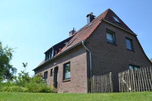 ein altes Backsteinhaus mit einem Zaun davor in der Unterkunft NordApart - Butjadingen in Butjadingen