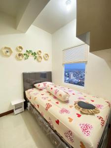 een groot bed in een slaapkamer met een raam bij TripleQ Room 2BR Vidaview Apartment in Makassar