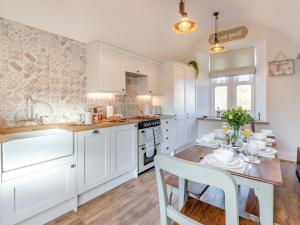 a kitchen with white cabinets and a wooden table at West House in Wooler