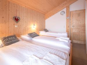 two beds in a room with wooden walls at Chalet Alpenpark Turracherhöhe 4 in Turracher Hohe