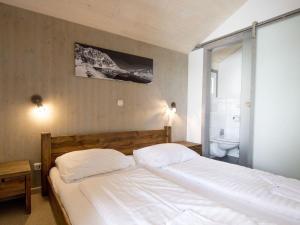 a bedroom with a white bed and a bathroom at Chalet Alpenpark Turracherhöhe 2 in Turracher Hohe