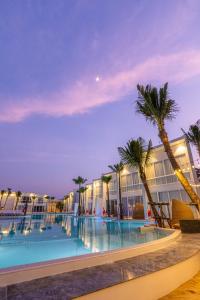 a swimming pool at night with palm trees and buildings at The Gems Mining Pool Villas Pattaya - SHA Extra Plus in Nong Prue