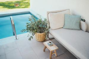 - un canapé et un tabouret à côté de la piscine dans l'établissement Magnolia Villas Thassos, à Potos