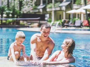a family sitting in the water in a swimming pool at Radisson Resort and Suites Phuket in Kamala Beach