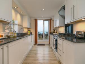 a kitchen with white cabinets and a view of the ocean at Laurellie in Carbis Bay