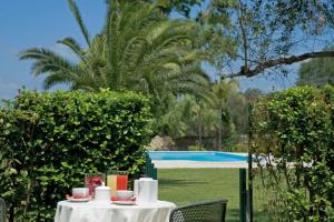 ein Tisch mit Tassen und Tellern neben einem Pool in der Unterkunft Tenuta Badessa in Casalabate