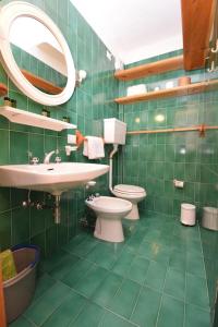 a green tiled bathroom with a sink and a toilet at Grazioso appartamento vicino al centro in Livigno