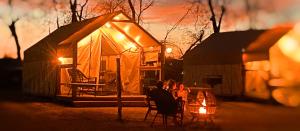 a tent with people sitting in front of it at night at Son's Rio Cibolo - Glamping Cabin #J Romantic Getaway on Gorgeous Cibolo Creek! in Marion